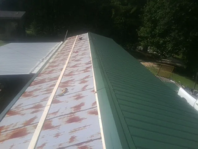 Old rusted panels beside newly installed green metal roofing — Wind Damage Roof Repair by Roofing Brothers in Westdale
