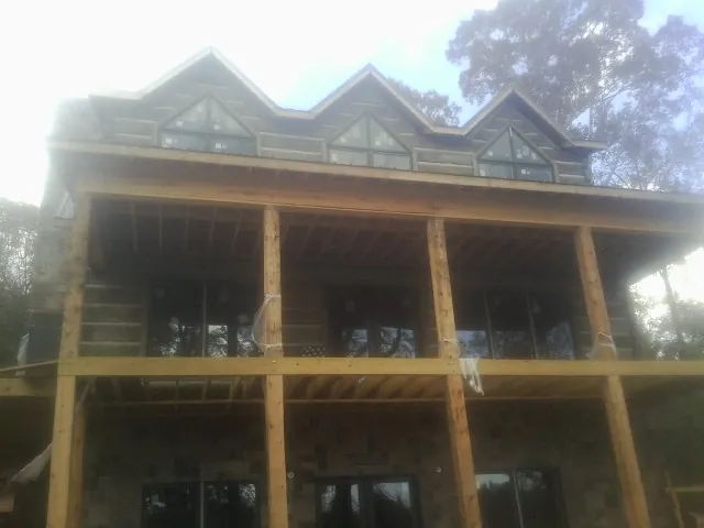 Dormers and porch framing on a large log home under construction — Roof Coating work by our crew in Westdale