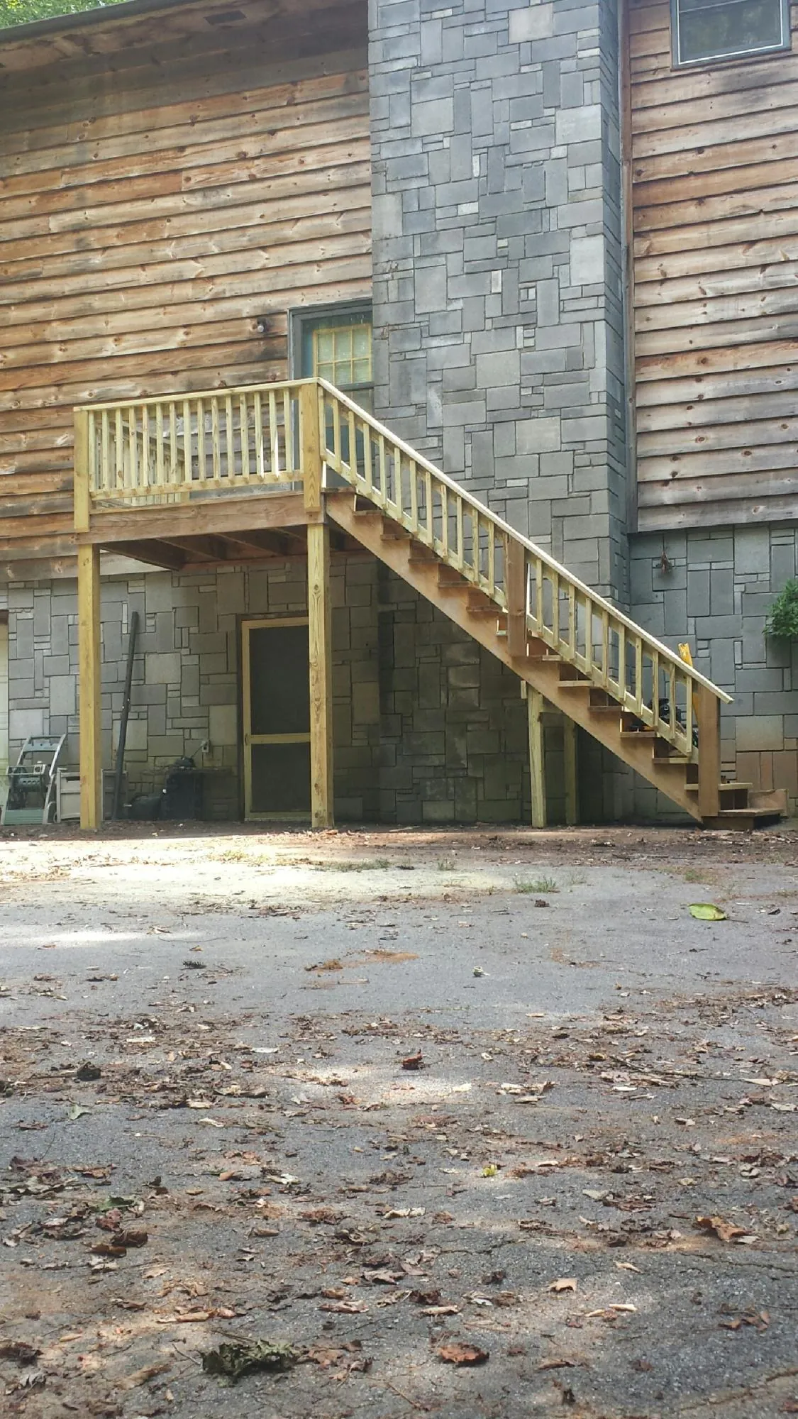 New pressure treated deck and stair landing on a log home in Westdale