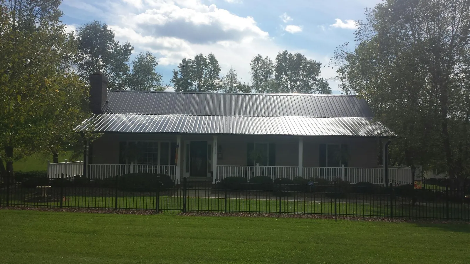 Gray metal roof on a brick ranch with a full width front porch — Gutter Guard Installation work by our crew in Westdale
